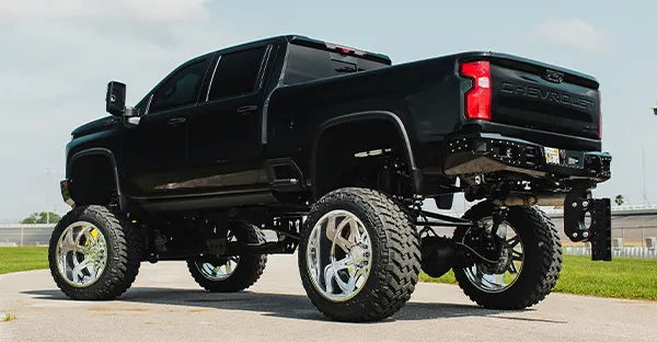Rear three-quarter view of Casey's black lifted 2020 Chevrolet Silverado 2500HD with polished wheels, install photo 4