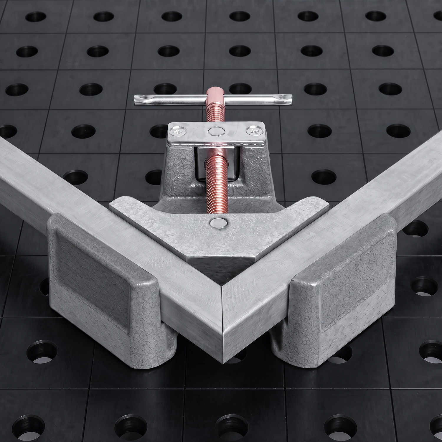 Metal fixture on a black work surface with holes for positioning.