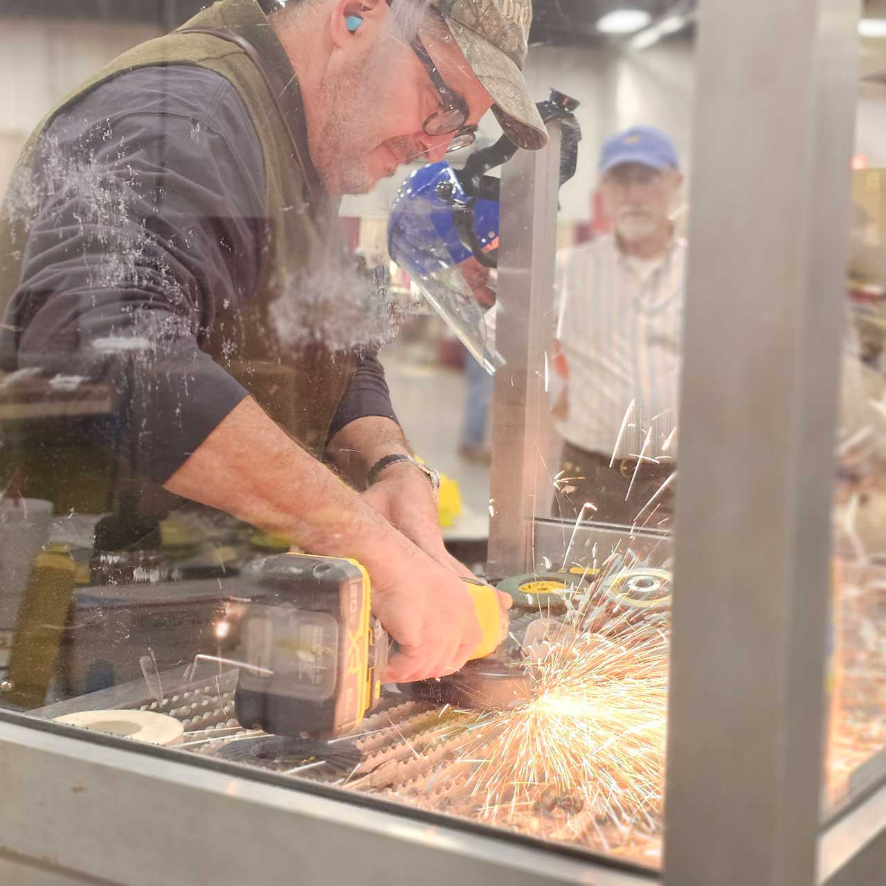 A man welding, sparks flying, in a workshop setting.