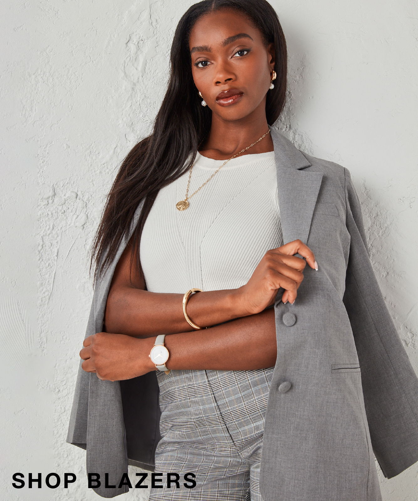Woman in a gray blazer and white top, posing against a light background.