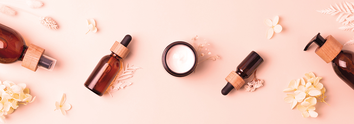Bottles and cream jar arranged on a pink background with decorative elements.