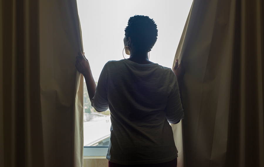woman closing curtains