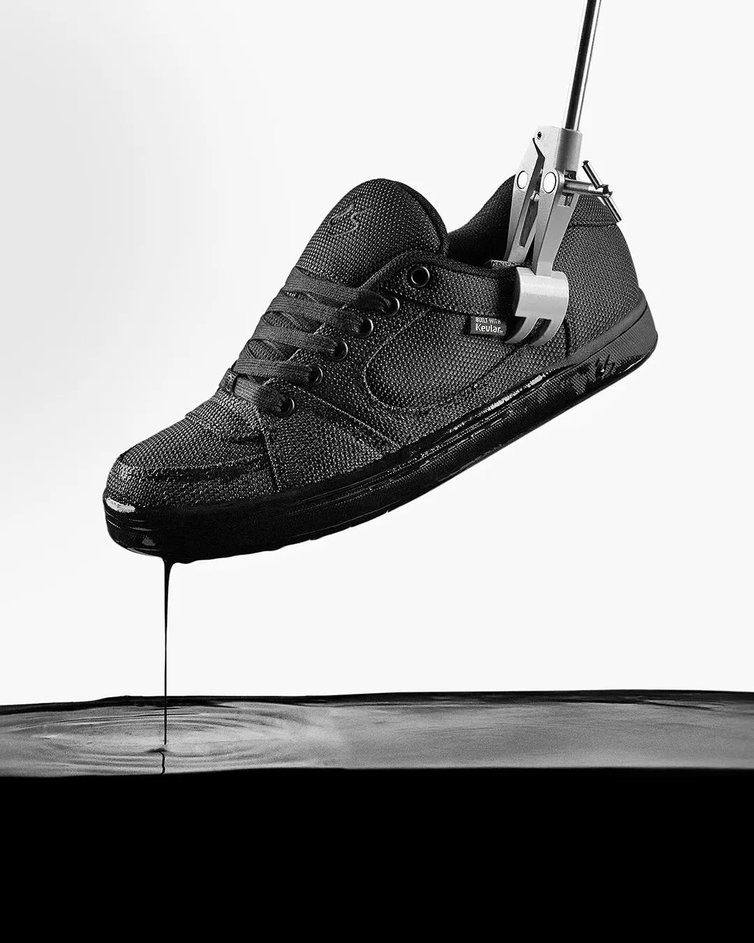 Black shoe hanging above a surface, dripping liquid below.