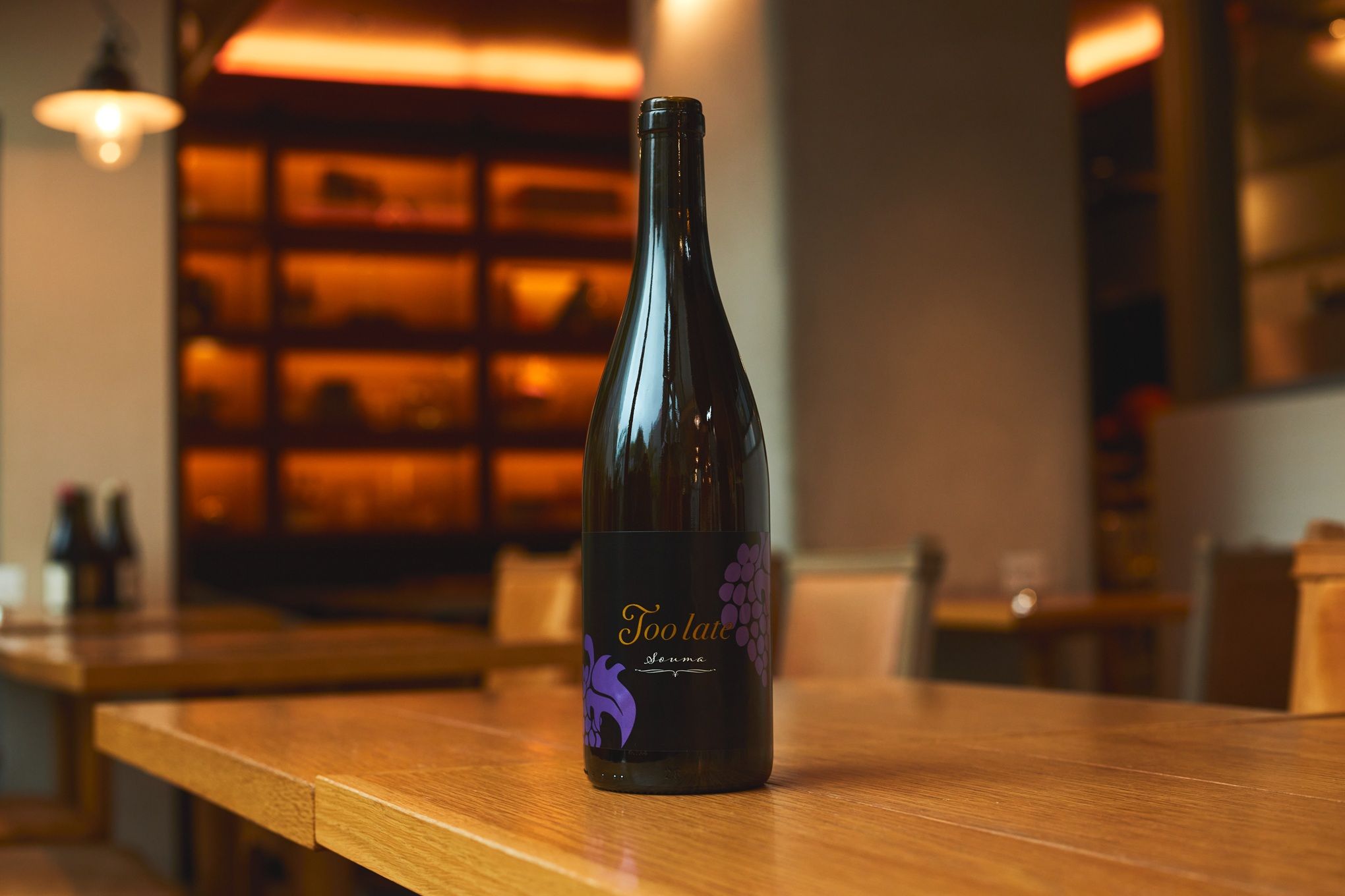 A wine bottle on a wooden table in a restaurant setting.
