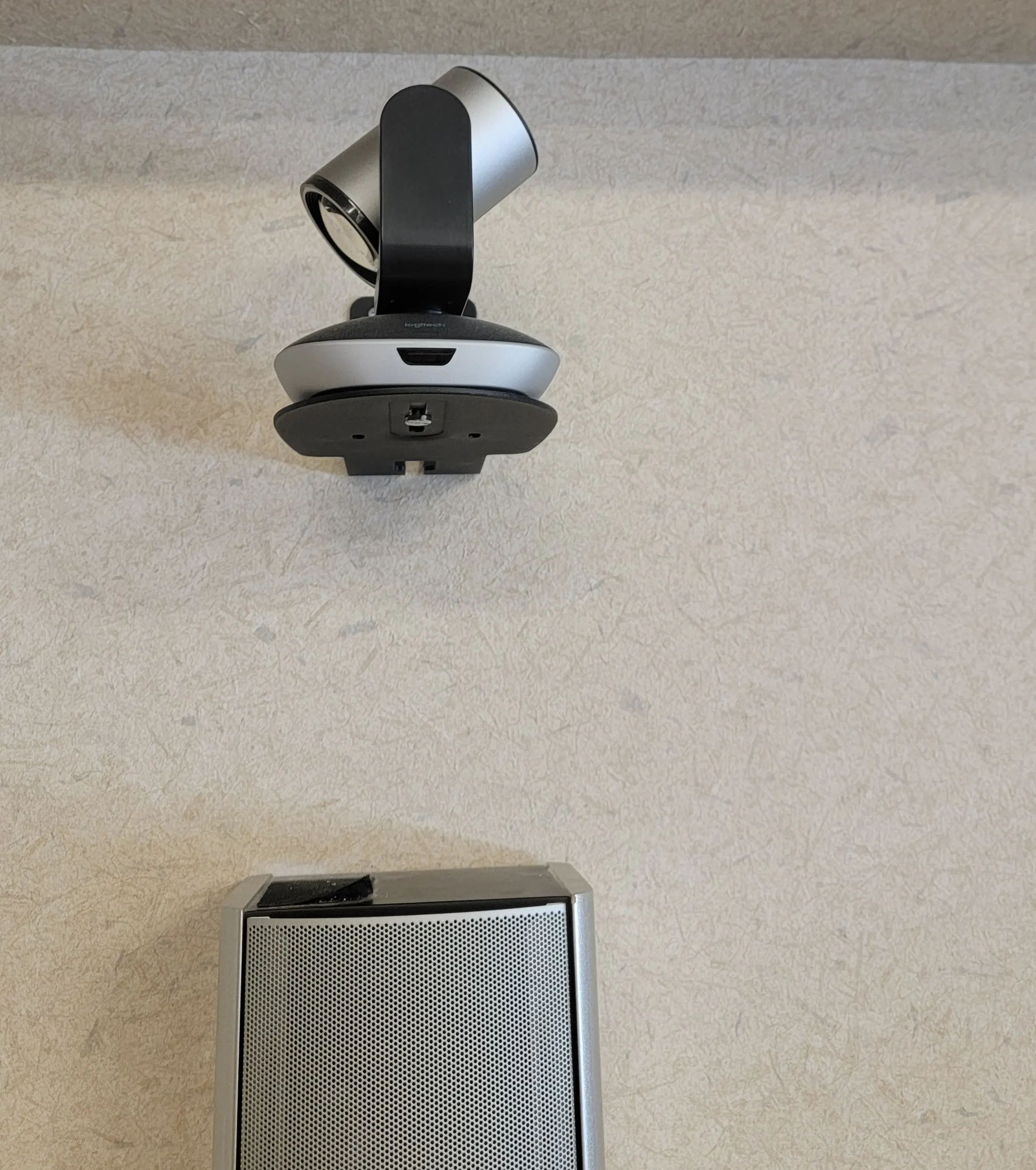 A gray device with a camera mounted above it on a light surface.