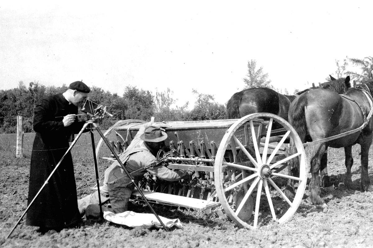Abbe Proulx taking a photo of a farmer fixing his horsepower tractor