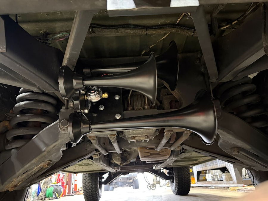 Low-angle undercarriage view three matte black Outlaw Train Horn trumpets mounted between frame rails on Greg's 2008 HMMWV Humvee with air solenoid gallery photo 2