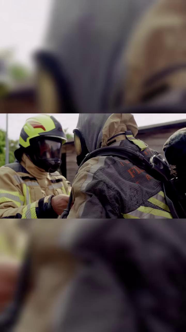 Firefighters preparing equipment in a smoky environment.