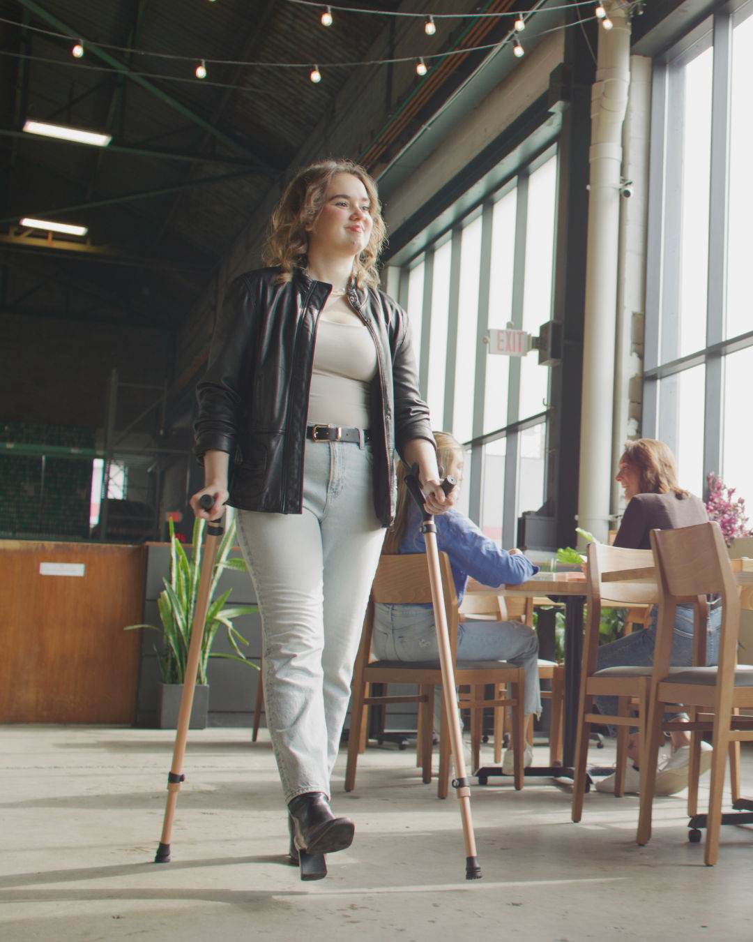 Woman walking through a café using a pair of Y-Canes in rose gold finish for bilateral support