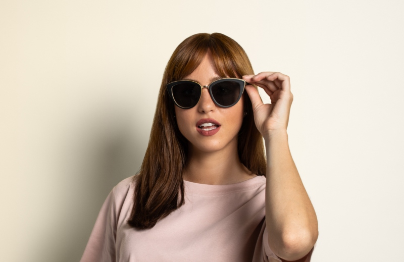 woman wearing Willow cat-eye sunglasses from Kraywoods heart face shape sunglasses collection on a pink background