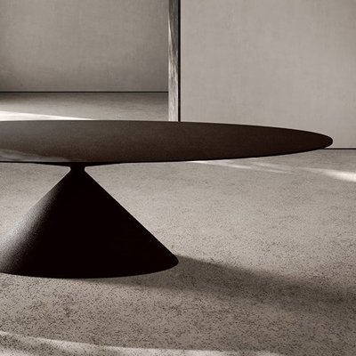 A modern, minimalist table with a cone-shaped base on a carpeted floor.