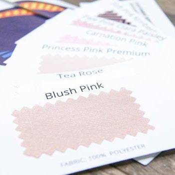 An assortment of pink fabric color swatches, including blush pink, on top of an envelope