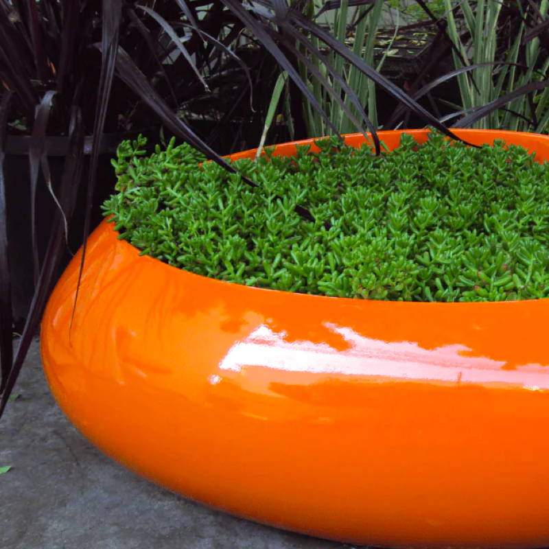 A bright orange high-gloss pebble shaped outdoor planter.