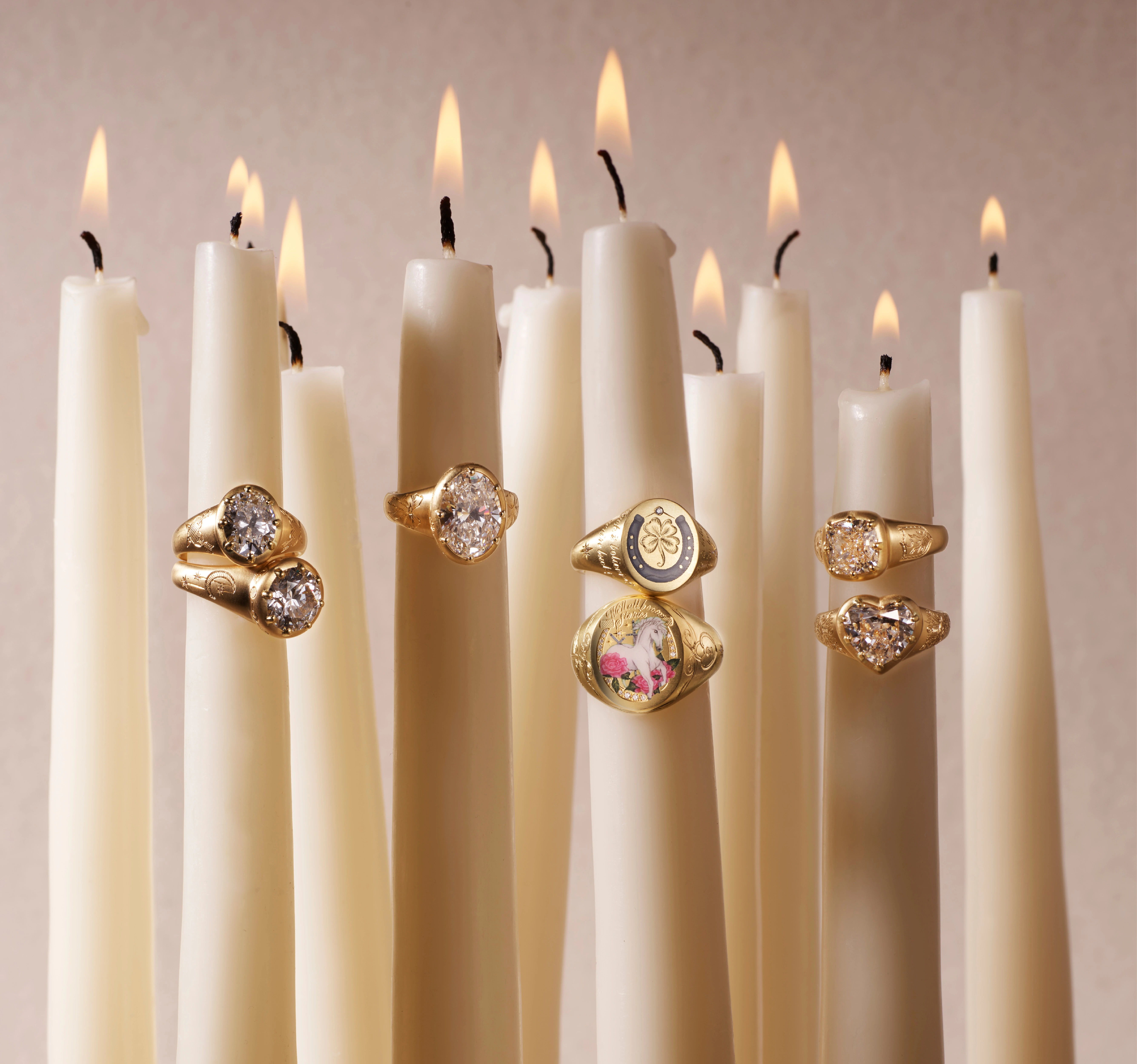 Rings displayed on lit candles against a soft background.