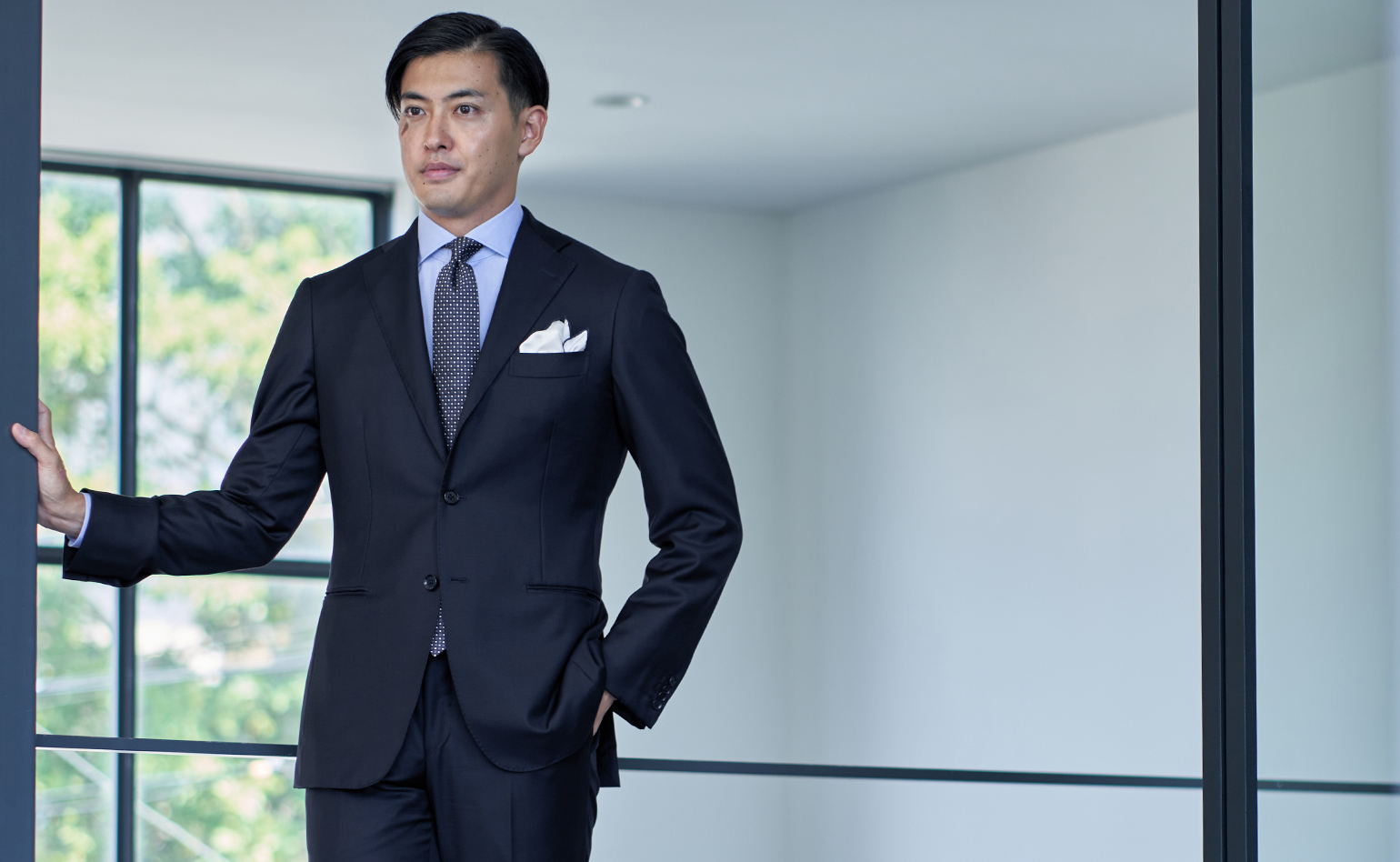 Man in a suit standing confidently in a modern interior space.