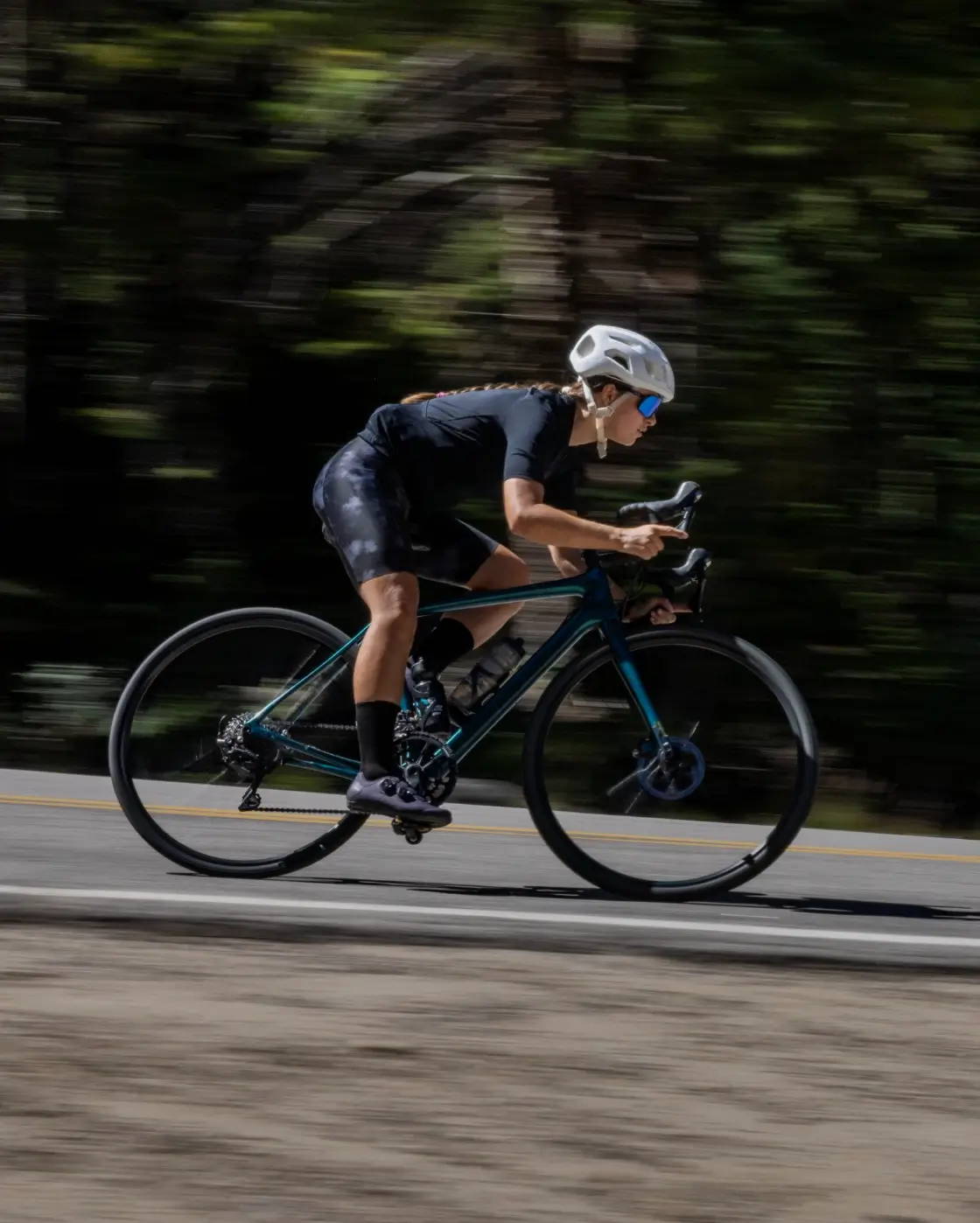 Female road cyclist riding fast down a road wearing PERL iZUMi cycling apparel
