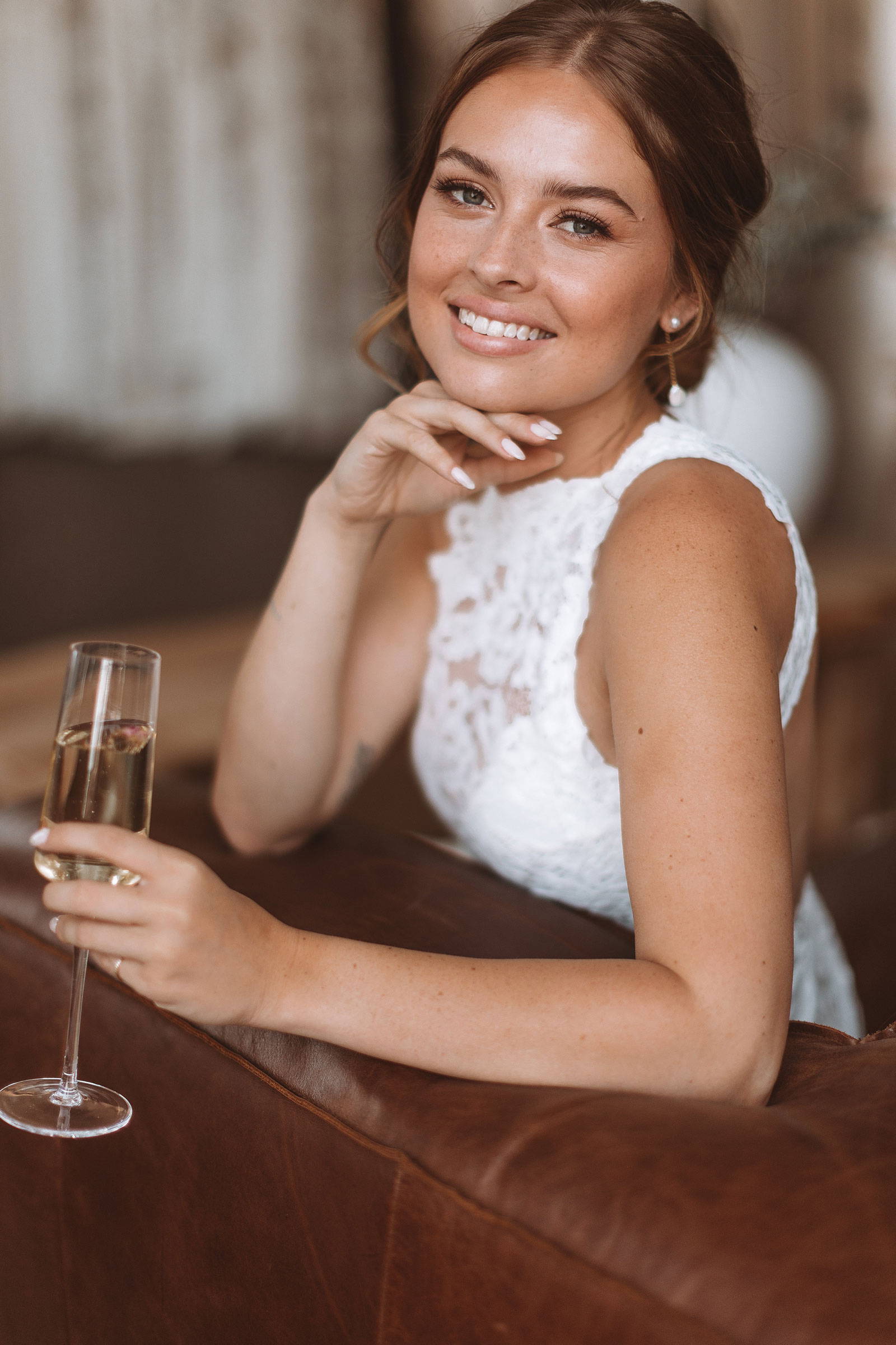 Bride wearing a high neck lace dress on leather couch