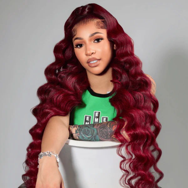 Young woman with long, wavy red hair extensions wearing a green top.
