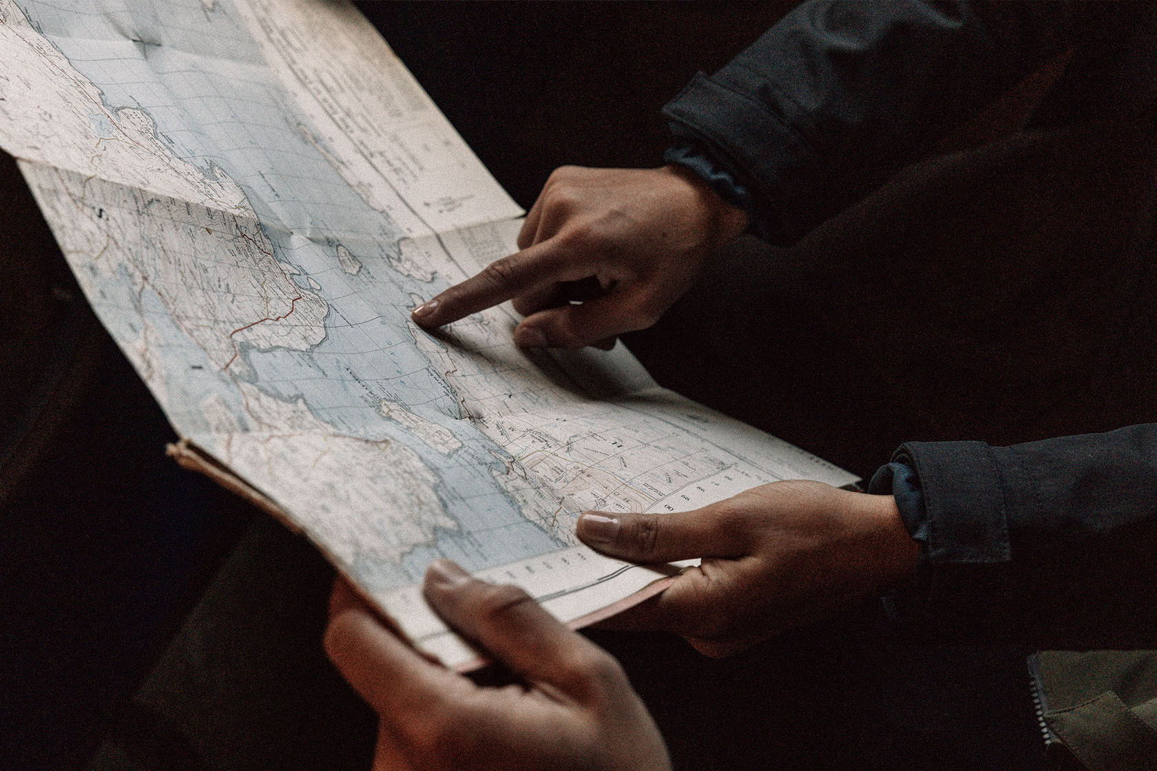 Hands pointing at a map with detailed geographic features.