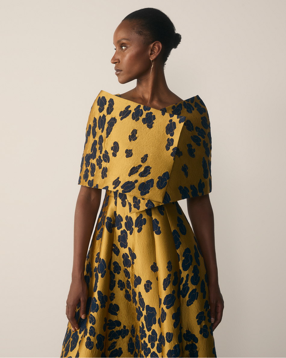 Model wearing gold and navy Bari wrap and Marsella gown