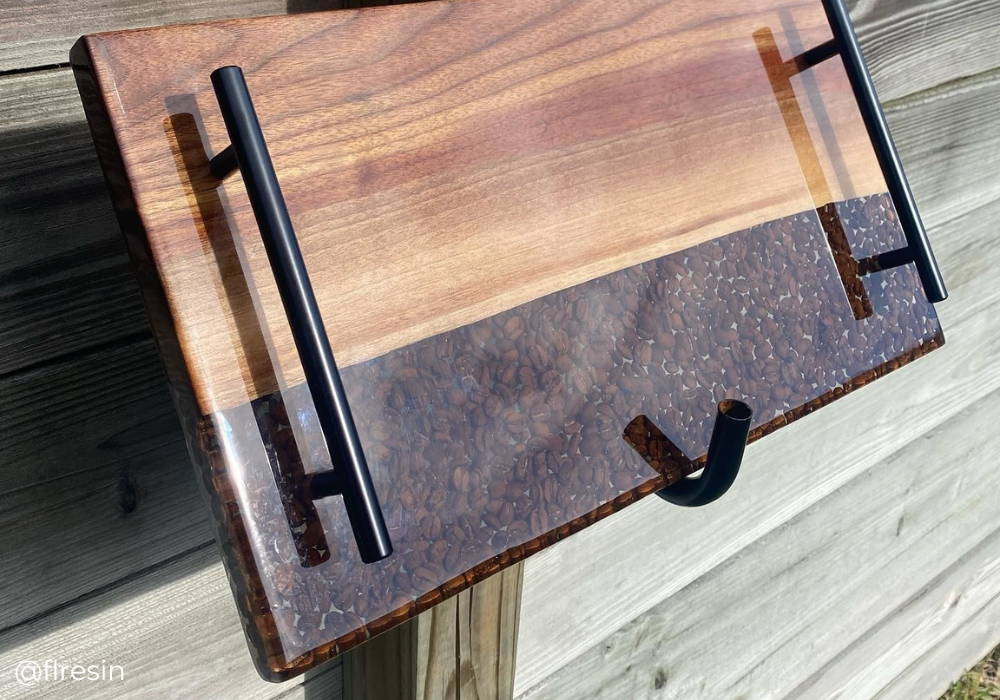 walnut wood and coffee bean encapsulated resin charcuterie tray with bronze handles mounted on a wooden wall