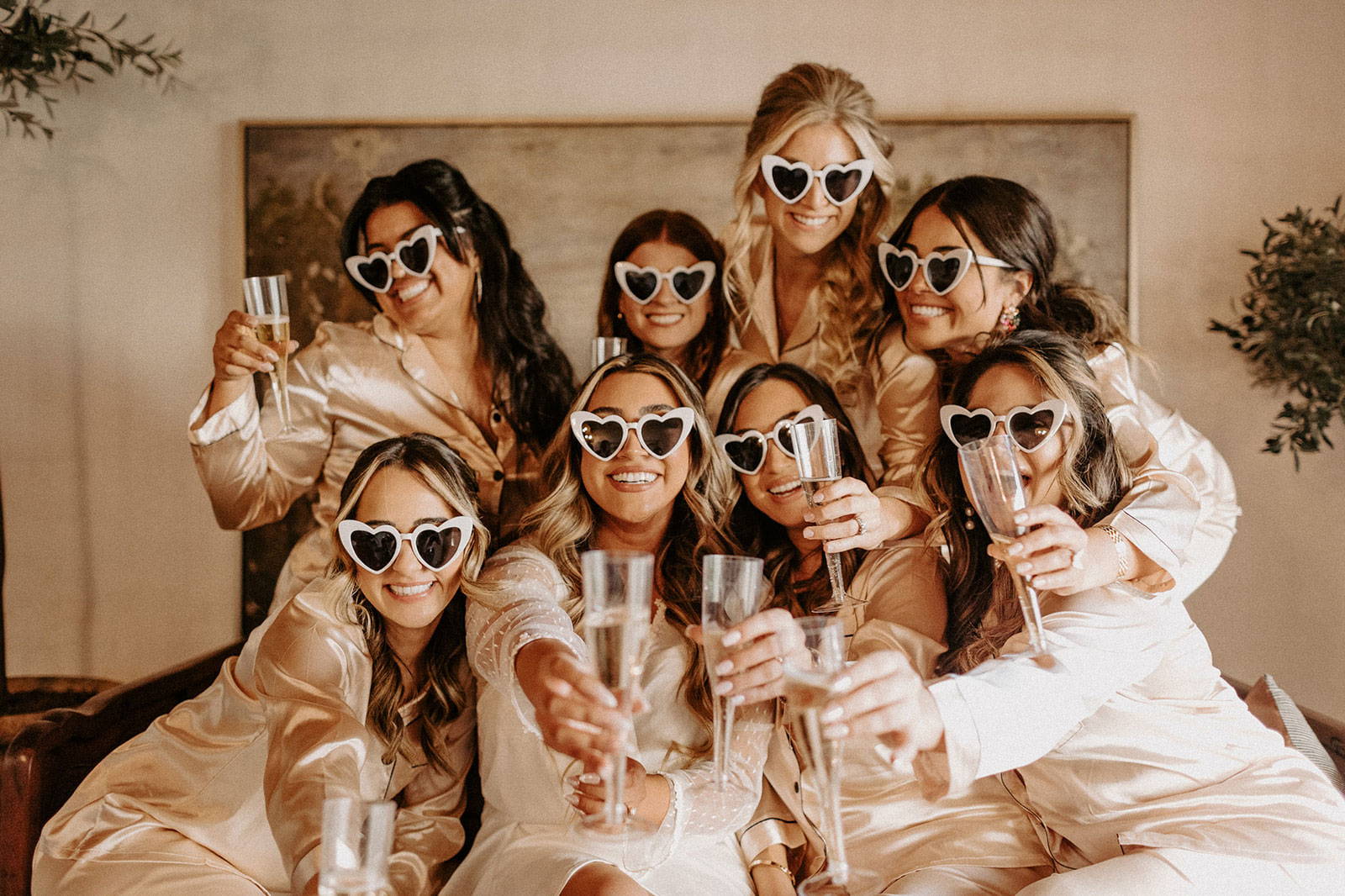 Les mariés portent des lunettes de soleil en forme de cœur et tiennent du champagne.
