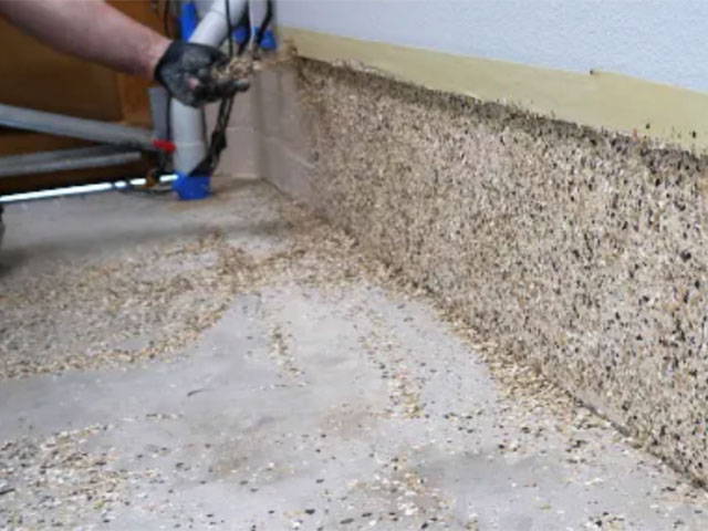 Evenly sprinkling flake onto garage walls, removing excess with a putty knife, and preparing for moisture seal application.