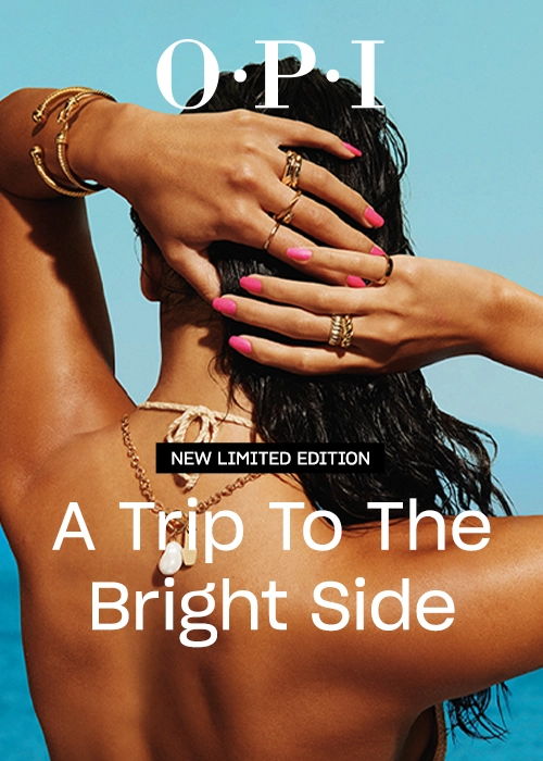 Woman with pink nails and jewelry by the ocean, promoting OPI nail polish.