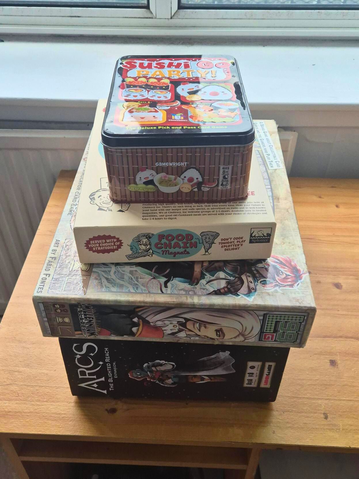 A stack of vintage boxes and games on a wooden surface.