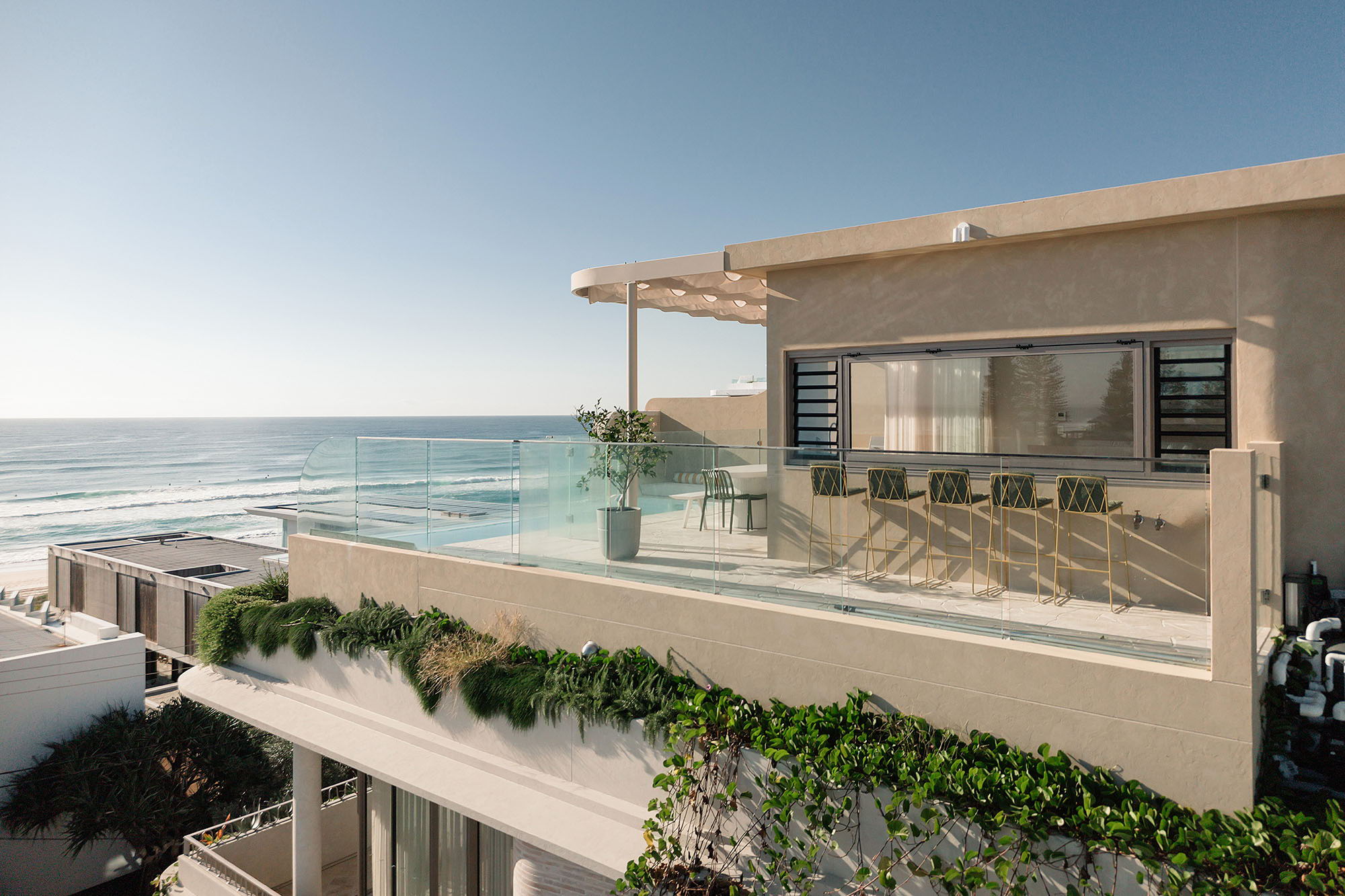 Modern seaside house with a balcony overlooking the ocean.