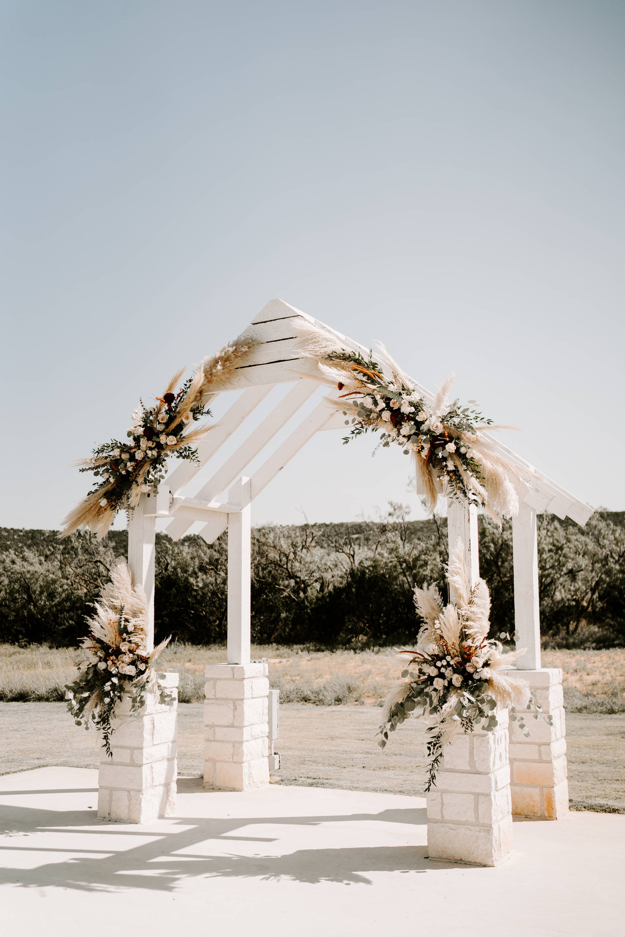 White wooden arbor decorated with coloured florals