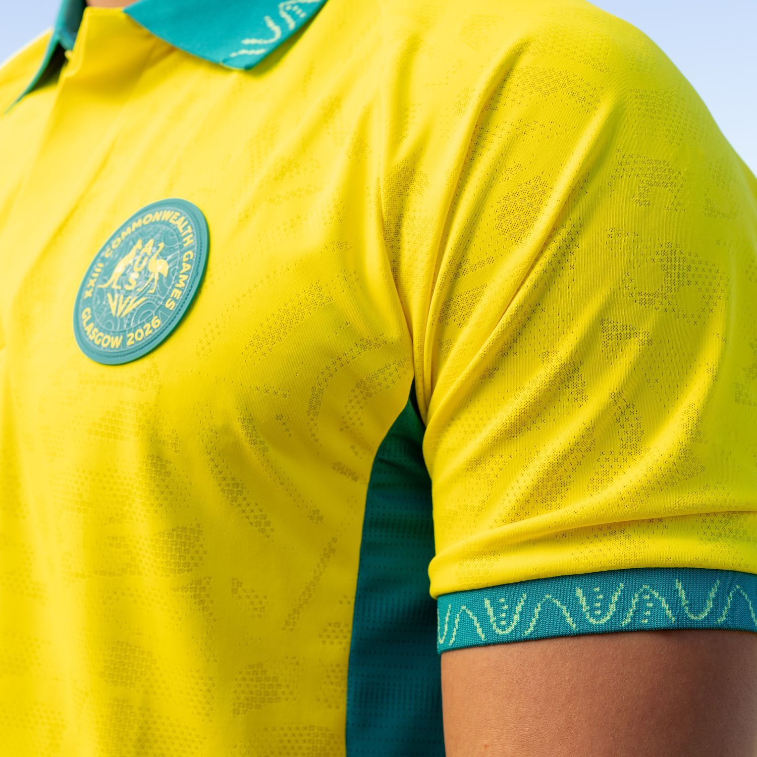 Close-up of a yellow polo shirt with green accents and logo.
