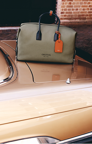 A green bag with a tag resting on a beige car.