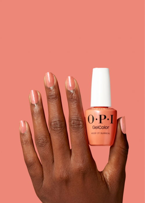 A hand holding an O.P.I nail polish bottle against a coral background.
