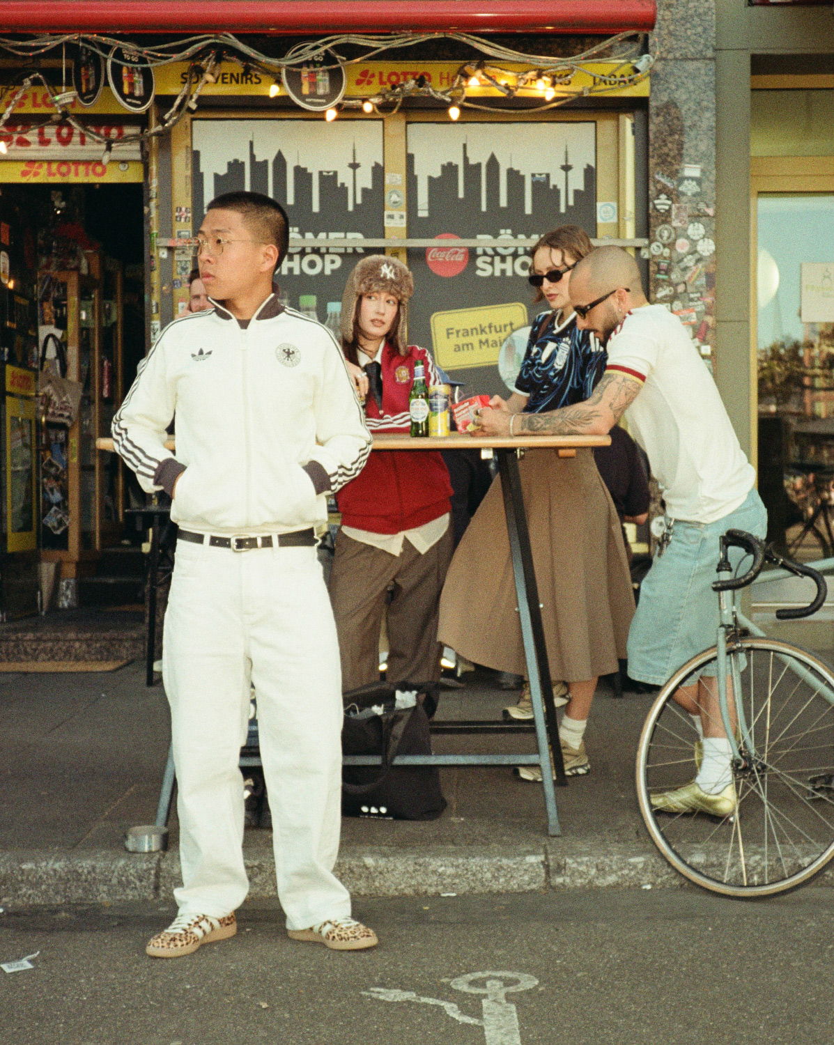 Group of people outside a shop, engaged in conversation and activities.