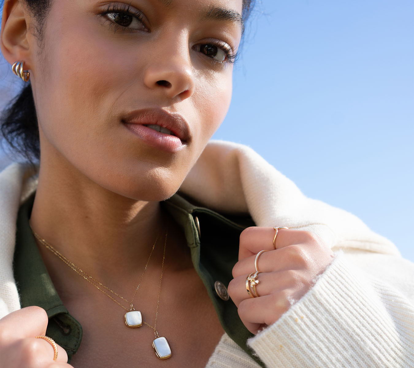 A woman wearing jewelry against a clear blue sky.