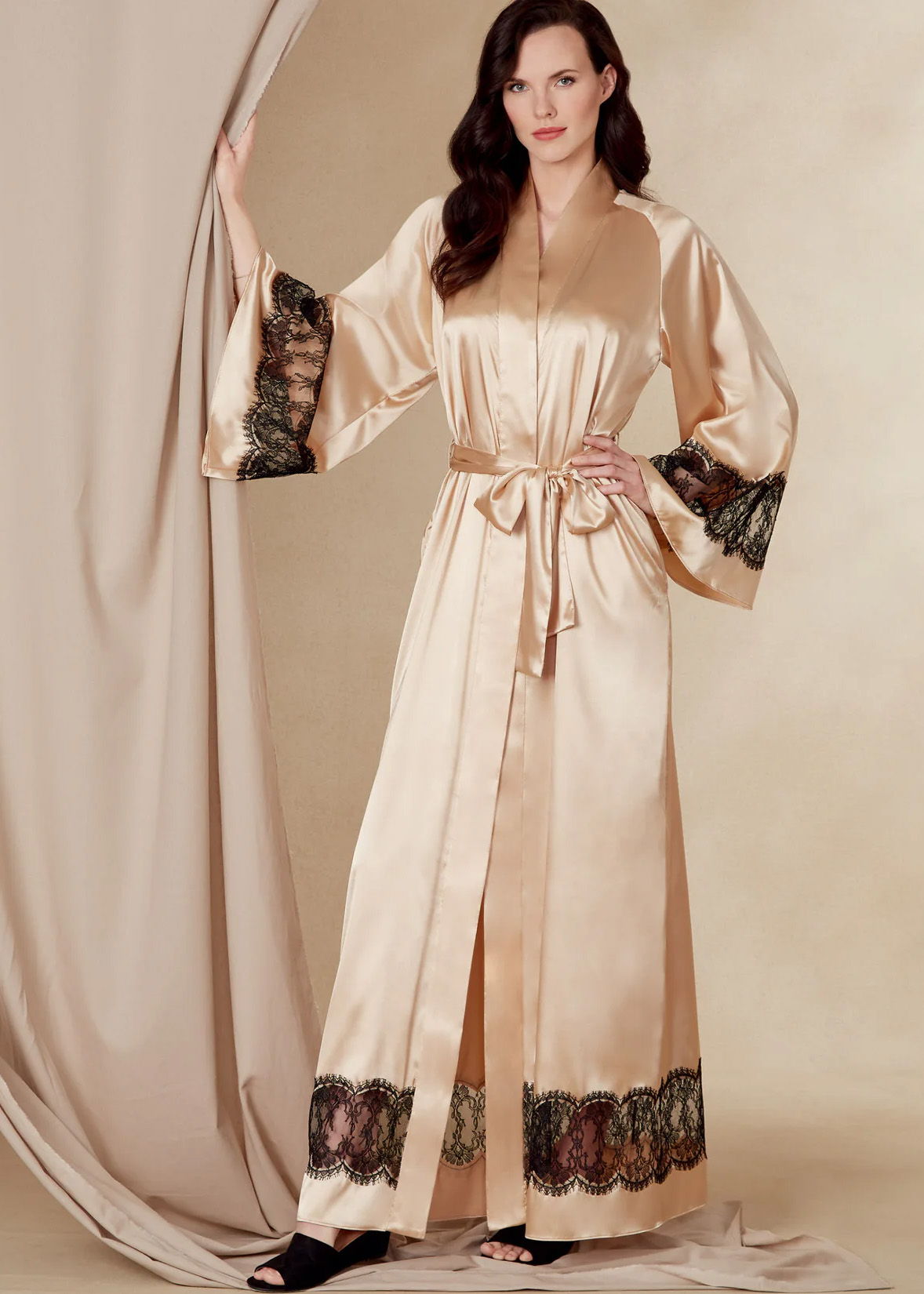 Woman wearing a satin robe with decorative sleeves and a tied waist.