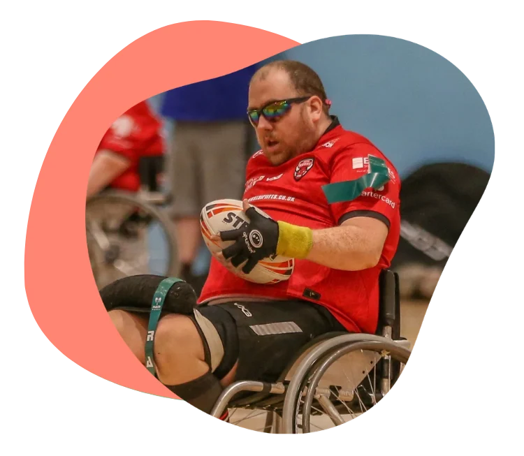 Athlete in wheelchair rugby focused on gameplay, wearing a red jersey.
