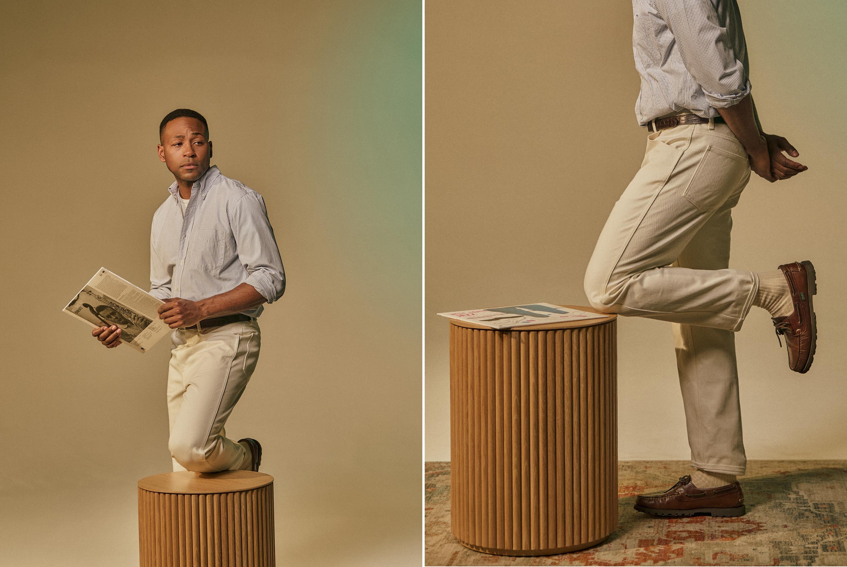 Man standing on a stool, holding a book, in a studio setting.