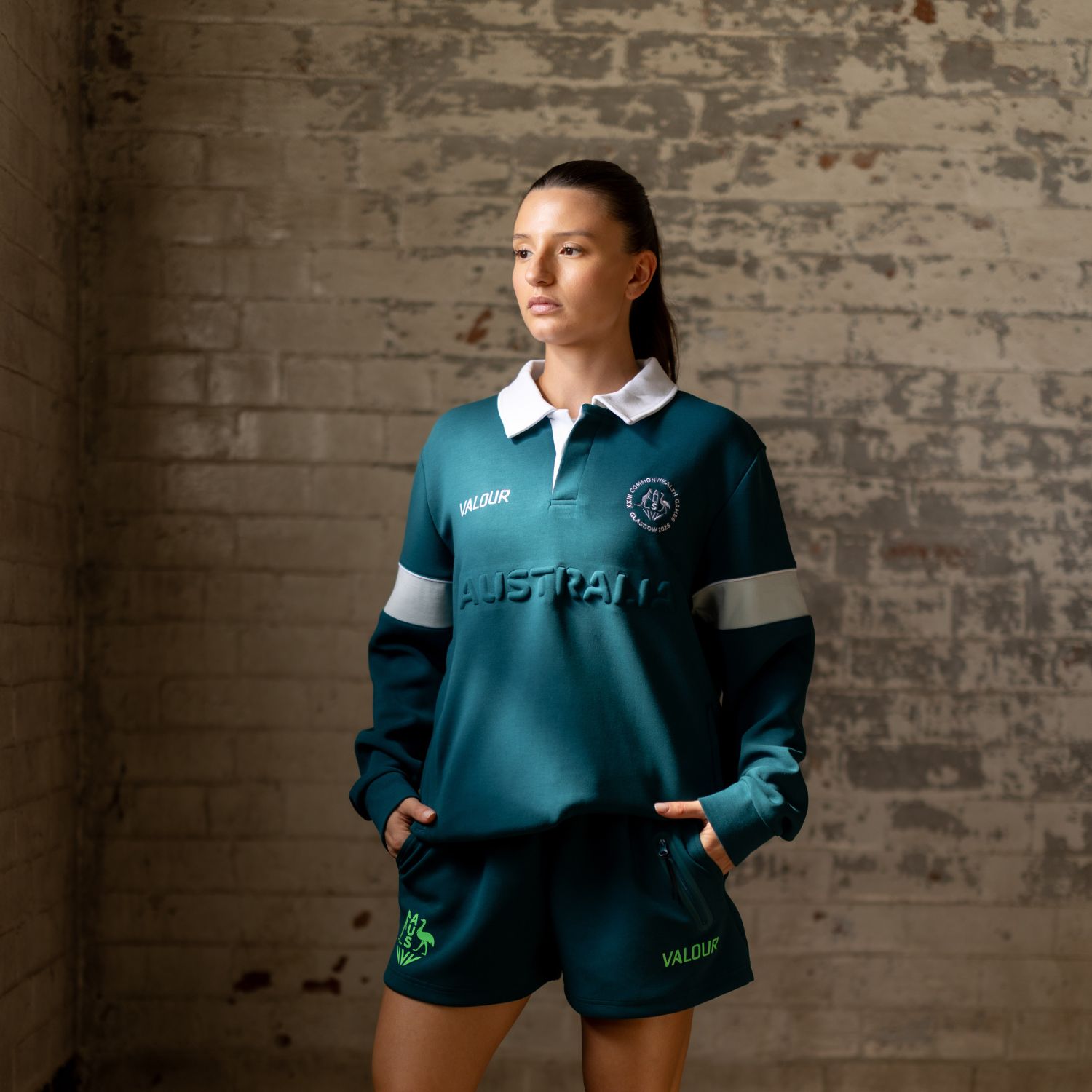Athlete in teal sports uniform standing against a textured wall.