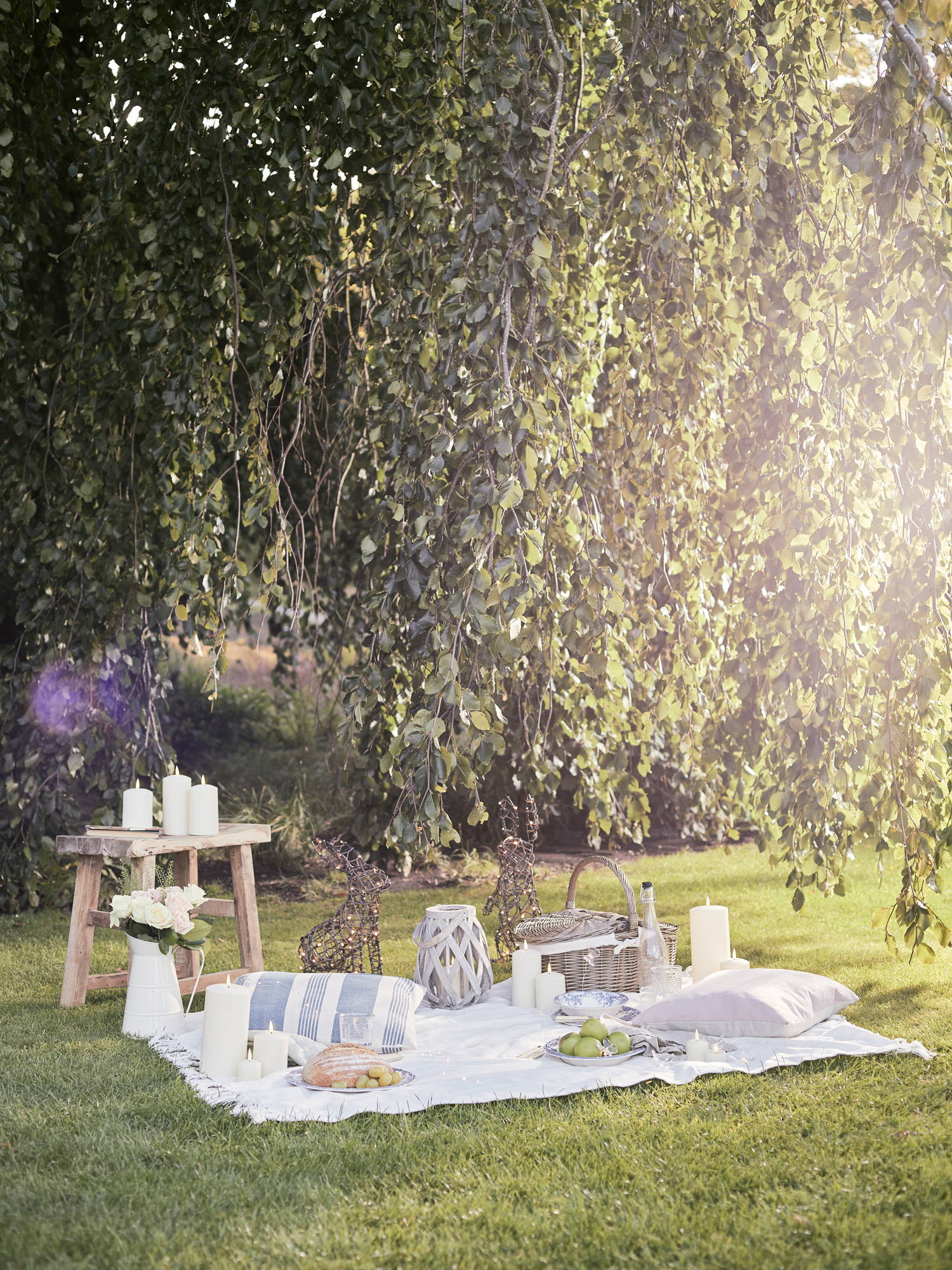 Spring picnic setting in garden with outdoor candles and lanterns