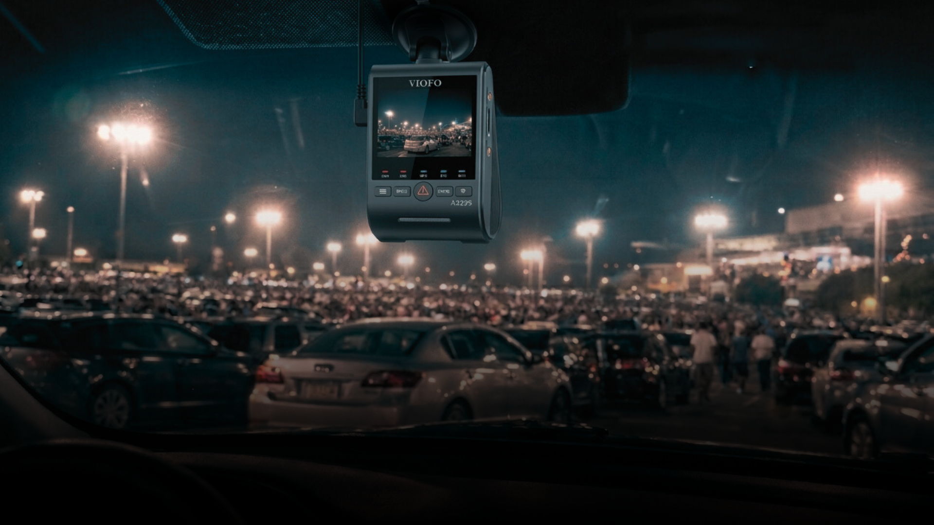 View from a car showing a crowded parking lot at night.