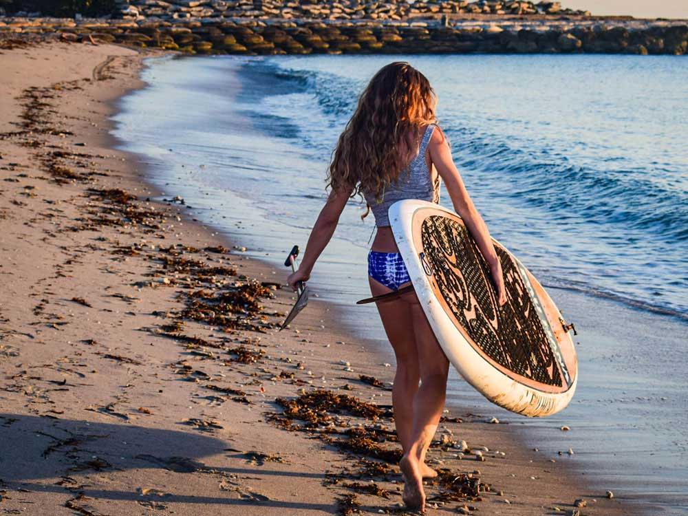 woman carrying the oahu paddleboard down the beach