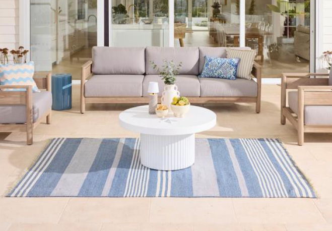 Outdoor seating area with a striped rug and coffee table.