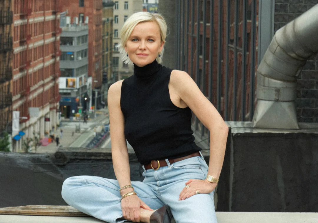 Person sitting on a rooftop with city buildings in the background.