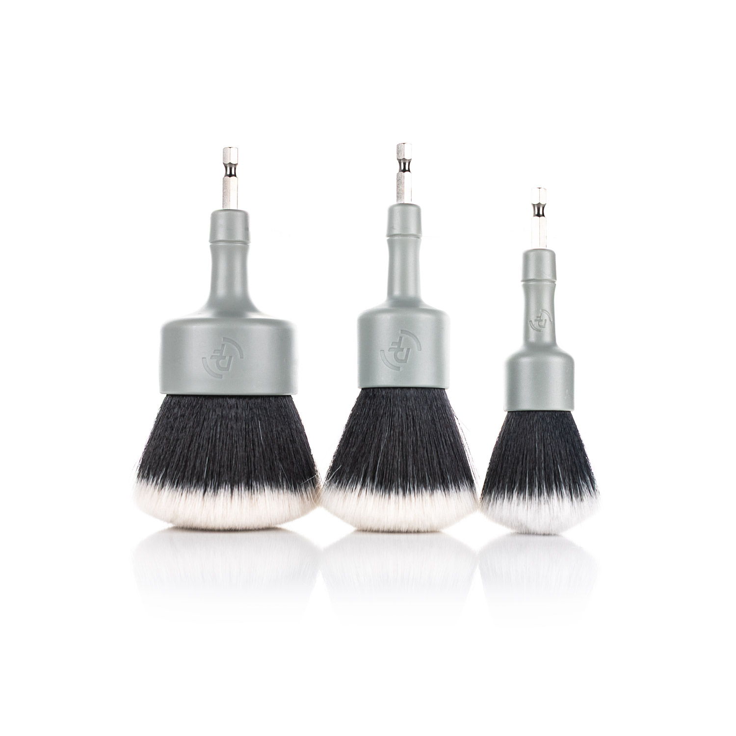 Three makeup brushes of varying sizes with silver handles and black bristles.