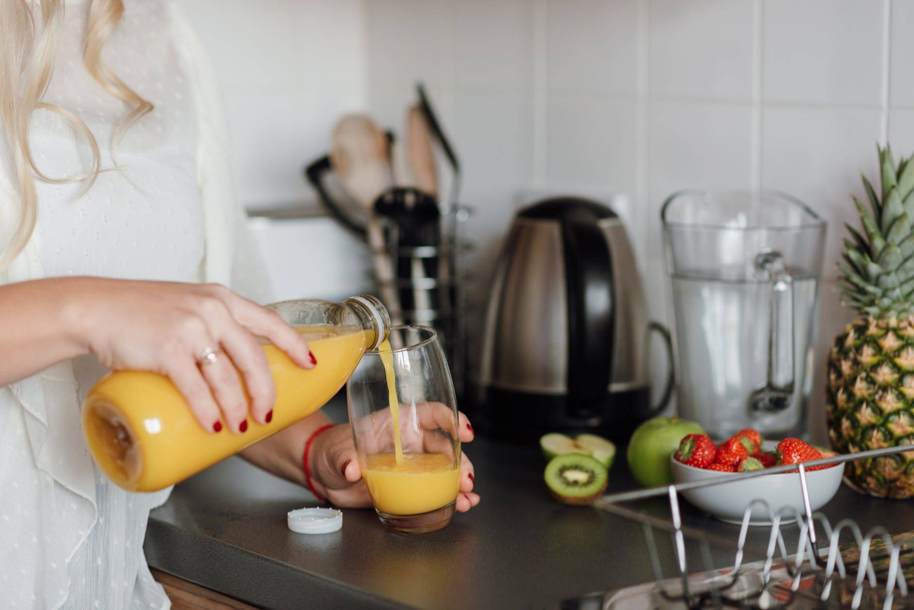 Woman Pouring Juice Standing Near Table With Fruits