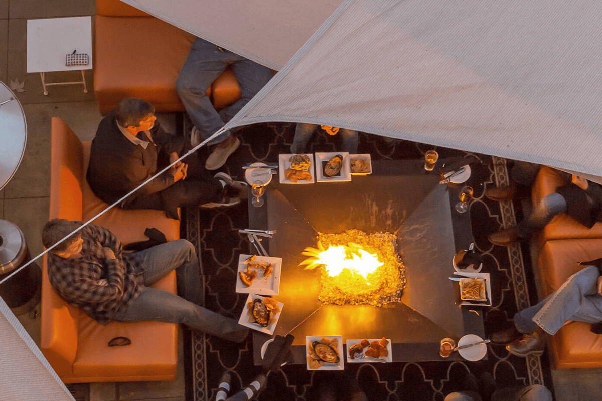 A bird's eye view of people gathered around a fire pit eating.