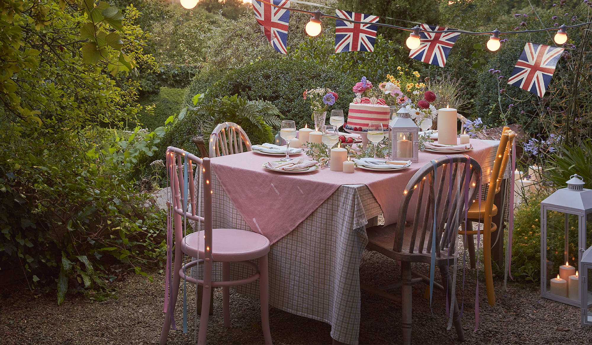 An outdoor coronation garden party with festoon lights, LED candles, Union Jack bunting and micro fairy lights.