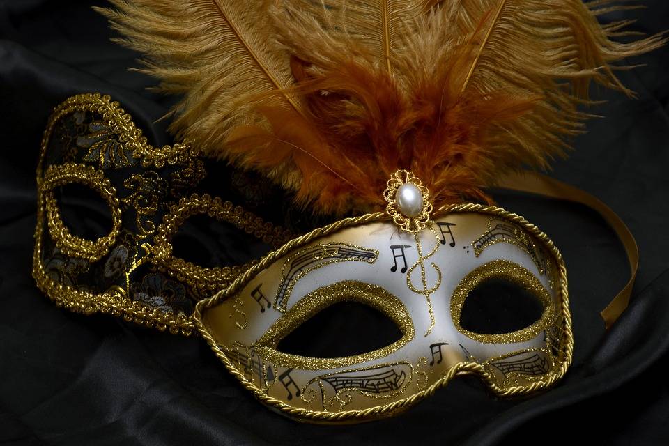 Image of white and gold masquerade mask with music notes and feathers at the top. 